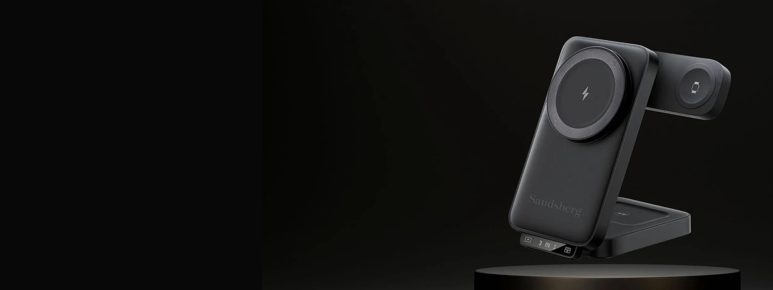 Zwarte 3-in-1 draadloze oplaadstation van Sandsberg met laadplekken voor telefoon, horloge en oordopjes, gepresenteerd op een donker voetstuk.